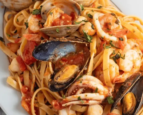 Un piatto invitante di scialatielli ai frutti di mare, con gamberi, cozze, vongole e calamari in un sugo rosso.