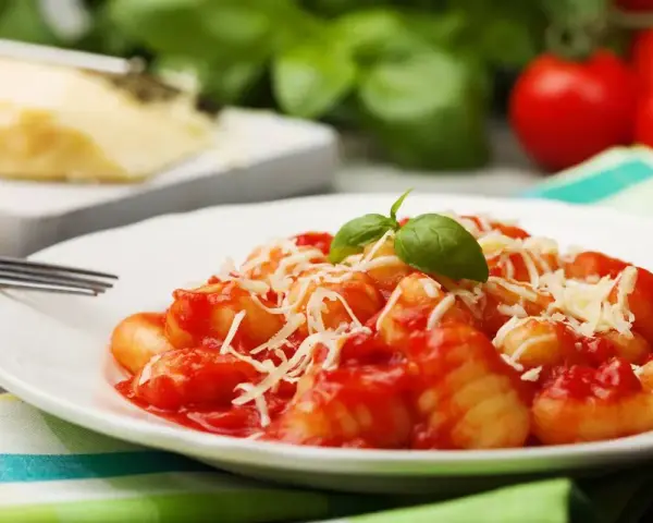 Gnocchi al pomodoro, un piatto semplice e gustoso, con basilico fresco e parmigiano grattugiato.