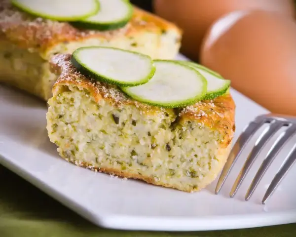 Delizioso sformato di zucchine, soffice e profumato, guarnito con fette di zucchina fresca. Perfetto per un pasto leggero.