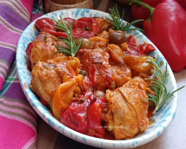 Un invitante pollo con peperoni alla siciliana, arricchito da olive e rosmarino, servito in un piatto decorato.