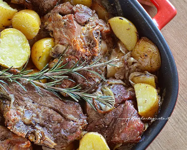 Agnello al forno con patate dorate e rosmarino, un piatto succulento pronto per essere gustato.