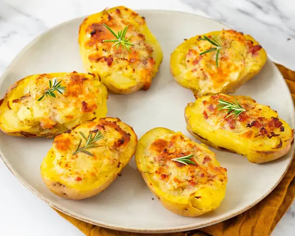 Patate ripiene al forno, dorate e gratinate, guarnite con rosmarino fresco. Un piatto invitante e saporito.
