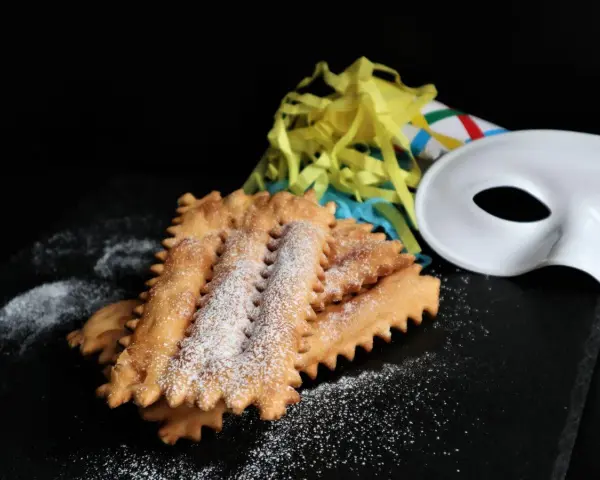 Chiacchiere siciliane spolverate di zucchero a velo, pronte per il Carnevale. La ricetta perfetta per festeggiare!