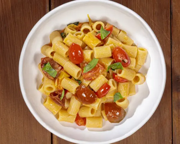 Un piatto invitante di pasta con pomodorini freschi, basilico e un filo d'olio.