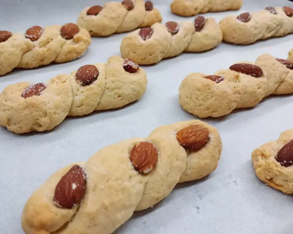 Intorchiate pugliesi ricetta originale: biscotti intrecciati dorati con mandorle e zucchero, pronti per essere gustati.