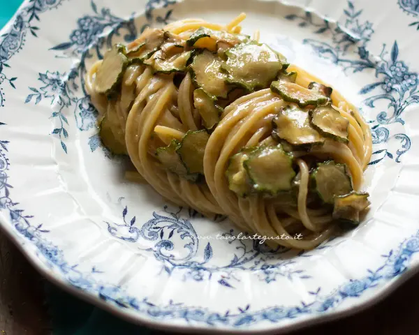 Spaghetti alla Nerano, un classico piatto campano con zucchine cremose e profumate, servito su un piatto decorato.