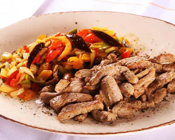 Straccetti di vitello succulenti serviti con un contorno colorato di verdure saltate, un piatto invitante e saporito.
