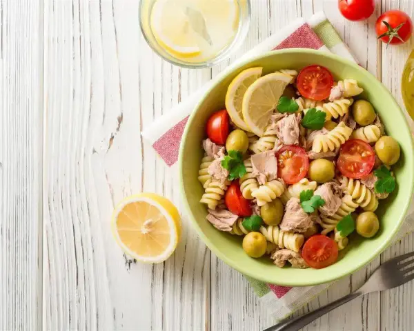 Deliziosa pasta fredda con tonno, pomodorini, olive e limone, perfetta per un pasto estivo.