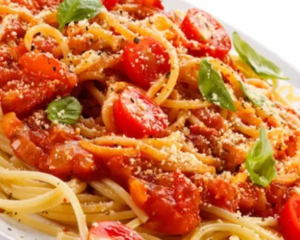 Un piatto di spaghetti alla carrettiera, conditi con pomodoro fresco, basilico e parmigiano grattugiato.