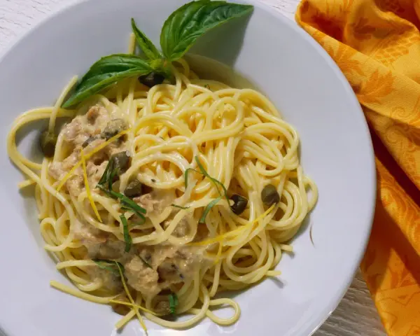 Spaghetti al tonno con capperi, scorza di limone e basilico, un piatto gustoso e profumato.