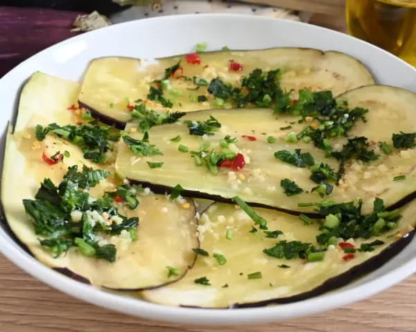 Fette di melanzane marinate crude, condite con aglio, prezzemolo e peperoncino.
