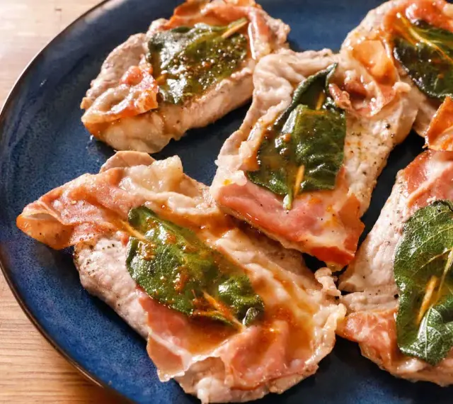 Saltimbocca alla romana: fettine di vitello con prosciutto crudo e salvia, cotte in padella con un sughetto dorato.