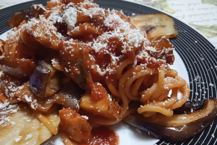 Un piatto invitante di pasta alla norma con melanzane fritte, sugo di pomodoro e ricotta salata grattugiata.