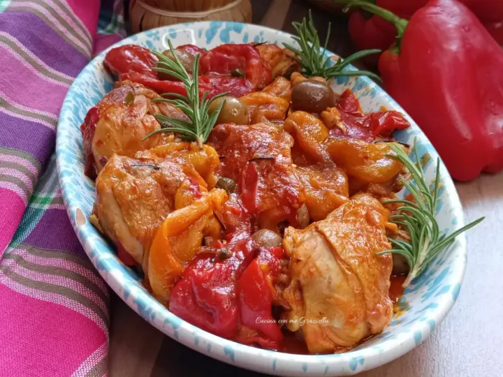 Un invitante pollo con peperoni alla siciliana, arricchito da olive e rosmarino, servito in un piatto decorato.