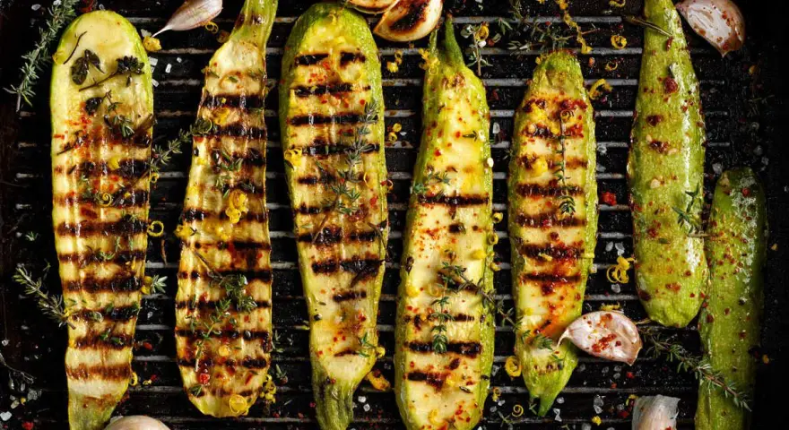 Zucchine grigliate perfette, condite con erbe aromatiche, aglio e scorza di limone, pronte per essere gustate.