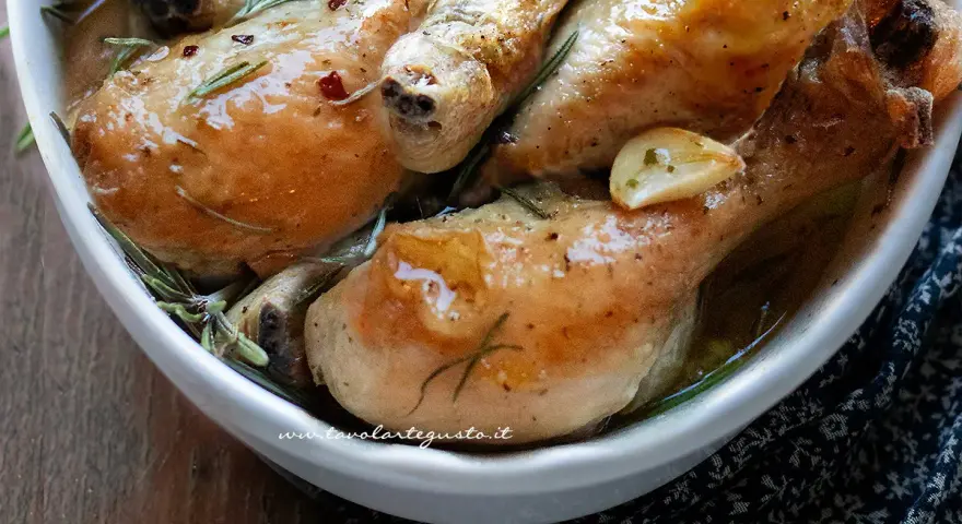 Cosce di pollo al forno succulente, dorate e profumate al rosmarino e aglio, servite in una ciotola bianca.