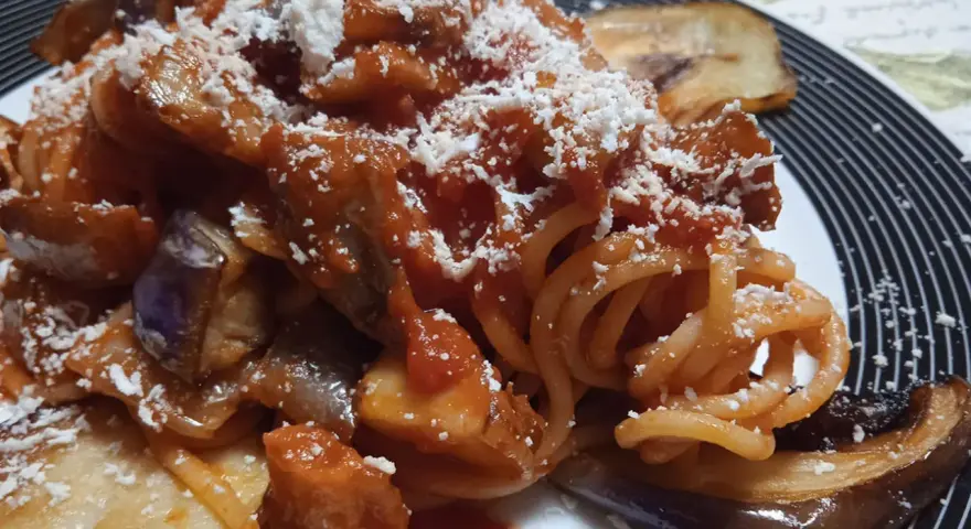 Un piatto invitante di pasta alla norma con melanzane fritte, sugo di pomodoro e ricotta salata grattugiata.