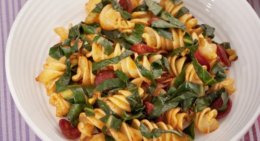 Fusilli conditi con bietole, salsiccia e un tocco di spezie. Un piatto saporito e colorato.