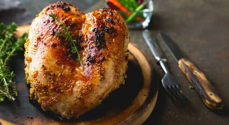 Succulento petto di pollo al forno, dorato e speziato, pronto per essere gustato con erbe aromatiche e peperoncini.