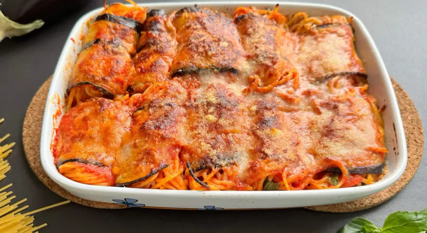 Involtini di melanzane con spaghetti al forno, ricoperti di sugo e formaggio filante, pronti per essere gustati.