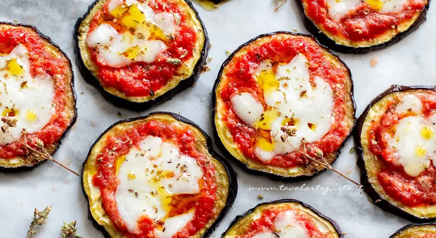 Pizzette di melanzane al forno, con pomodoro, mozzarella filante e un filo d'olio. Un antipasto sfizioso e leggero.