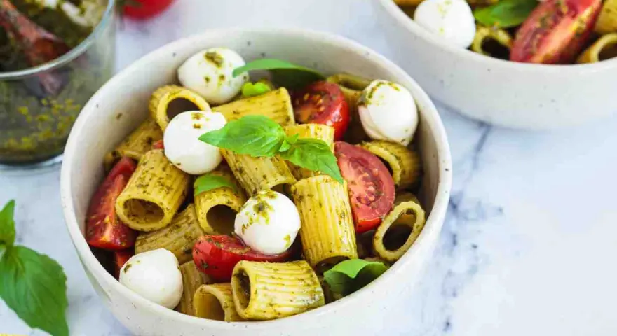 Un piatto di pasta pesto e pomodorini, con mozzarelline e basilico fresco. Un'esplosione di sapori mediterranei.