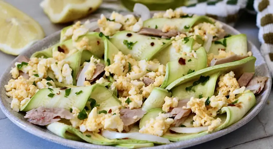 Deliziosa insalata di zucchine crude a nastro, condita con tonno, uova sode sbriciolate e prezzemolo fresco.