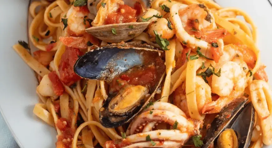 Un piatto invitante di scialatielli ai frutti di mare, con gamberi, cozze, vongole e calamari in un sugo rosso.