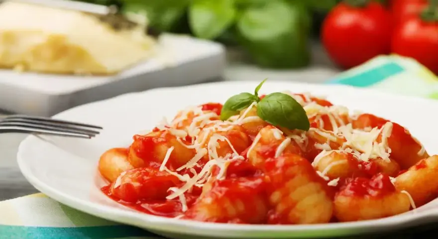 Gnocchi al pomodoro, un piatto semplice e gustoso, con basilico fresco e parmigiano grattugiato.