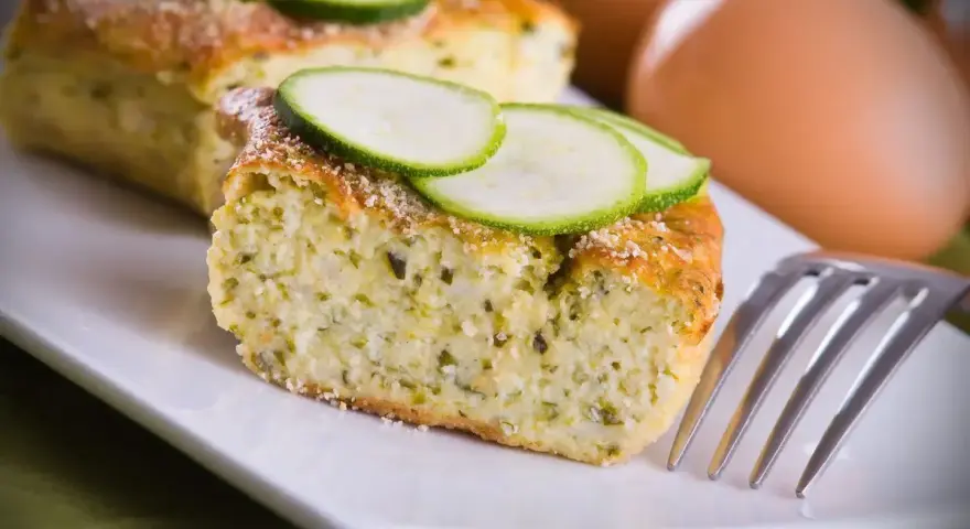 Delizioso sformato di zucchine, soffice e profumato, guarnito con fette di zucchina fresca. Perfetto per un pasto leggero.