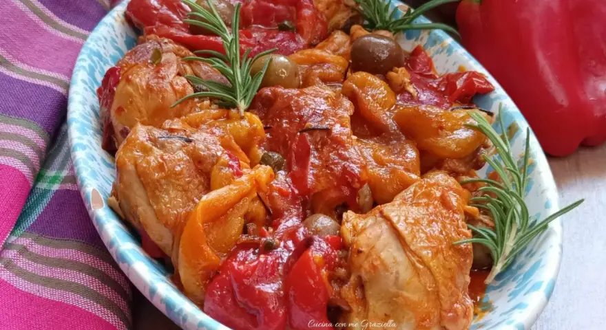 Un invitante pollo con peperoni alla siciliana, arricchito da olive e rosmarino, servito in un piatto decorato.