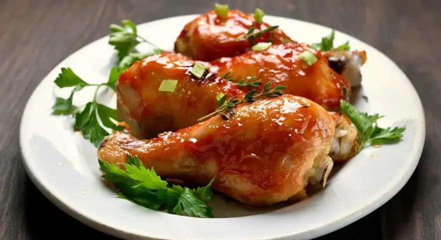 Tre succulenti cosce di pollo alla birra in padella, glassate e guarnite con erbe aromatiche e cipollotto.