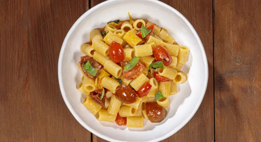 Un piatto invitante di pasta con pomodorini freschi, basilico e un filo d'olio.