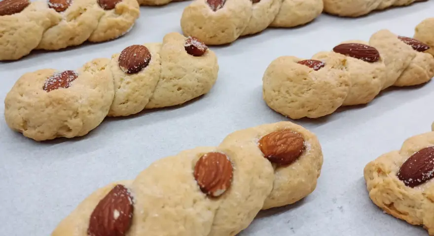 Intorchiate pugliesi ricetta originale: biscotti intrecciati dorati con mandorle e zucchero, pronti per essere gustati.