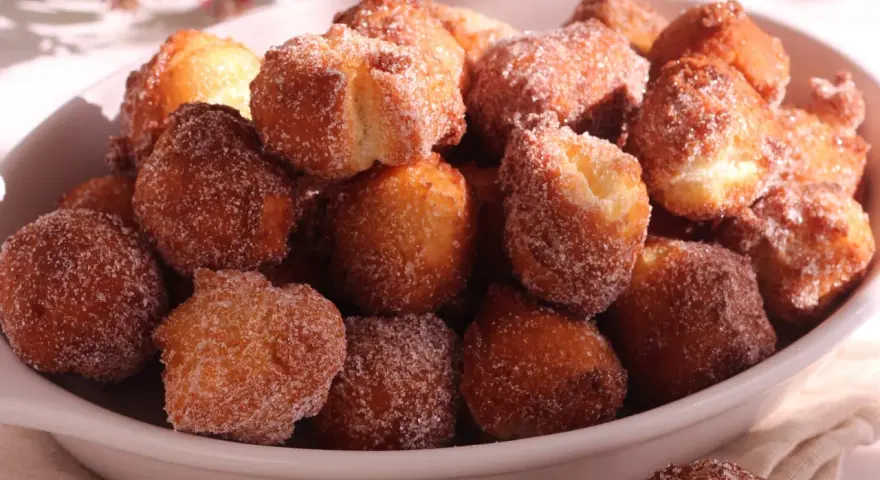 Un piatto colmo di castagnole ricetta della nonna, dorate e cosparse di zucchero. Un dolce che sa di casa e tradizione.