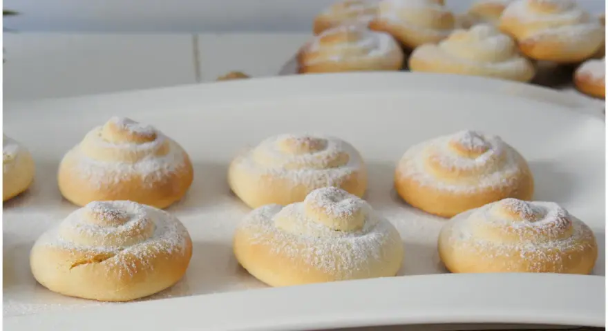 Biscotti a spirale cosparsi di zucchero a velo, perfetti con una tazza di caffè o tè, magari preparati con un tocco di latte condensato.