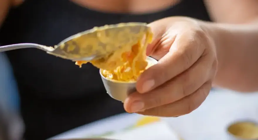 Una mano versa un cucchiaio di budino di riso in una coppetta.