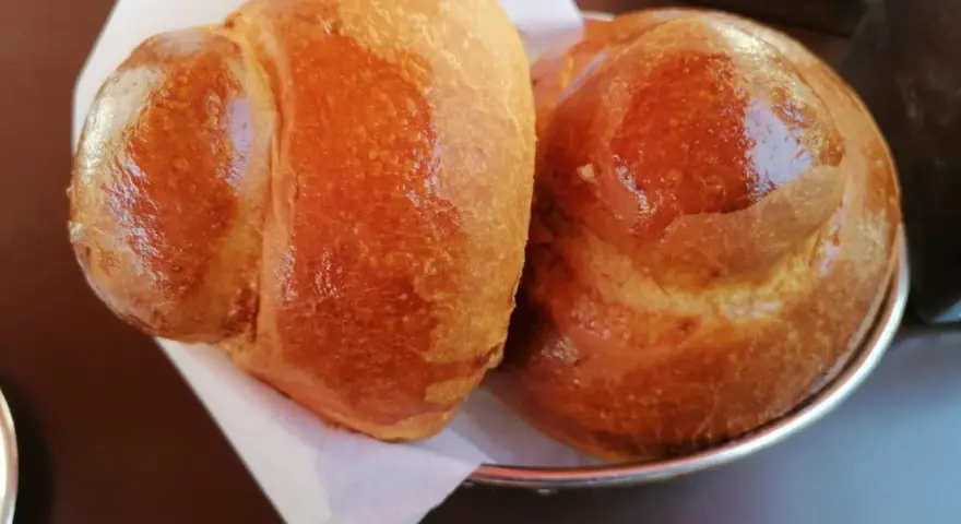 Due brioche col tuppo dorate e lucide, pronte per essere gustate con una granita.