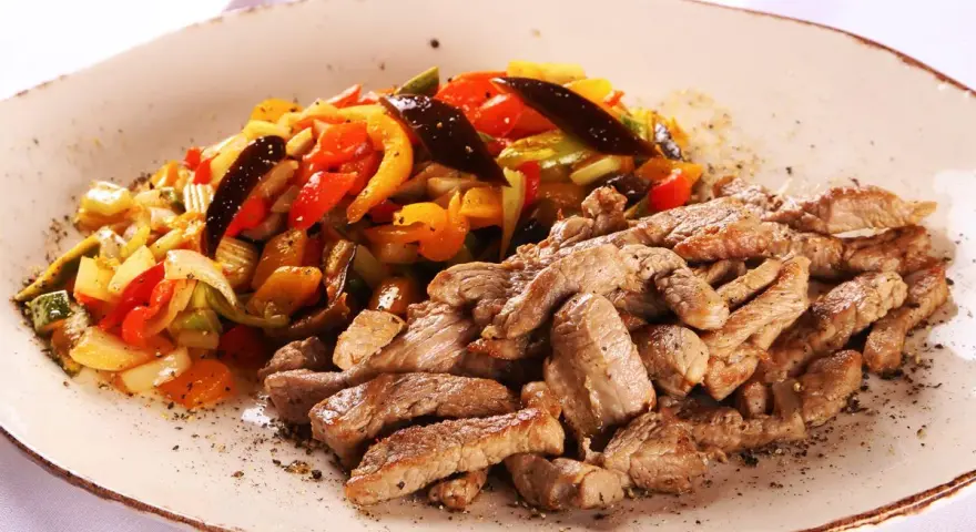 Straccetti di vitello succulenti serviti con un contorno colorato di verdure saltate, un piatto invitante e saporito.