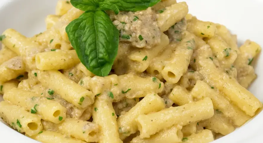 Un piatto invitante di pasta con melanzane in bianco cremosa, guarnito con basilico fresco.