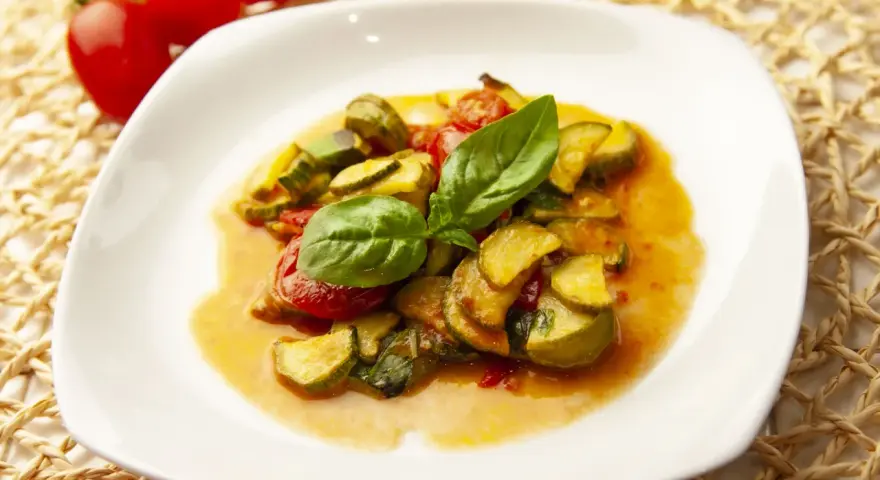 Zucchine in umido con pomodorini e basilico fresco, un piatto estivo profumato e saporito.
