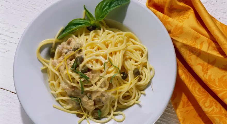 Spaghetti al tonno con capperi, scorza di limone e basilico, un piatto gustoso e profumato.