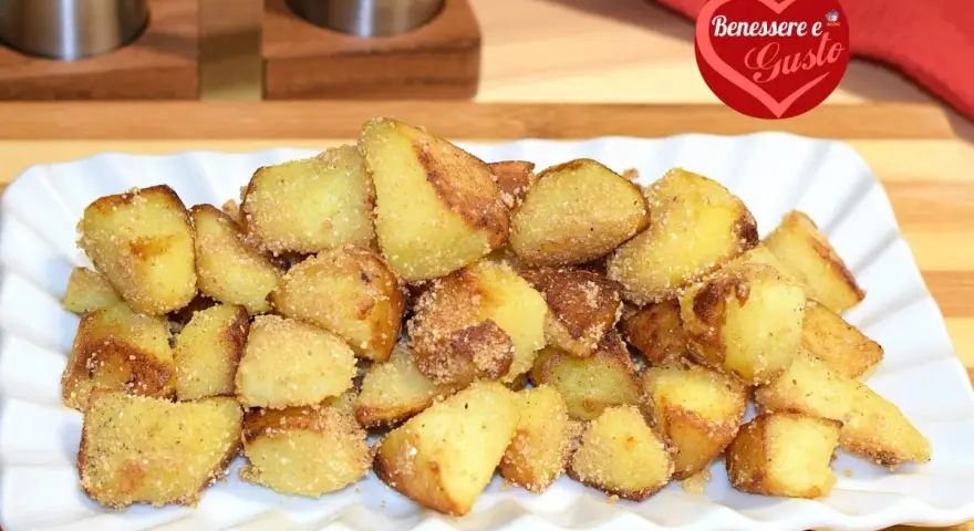Patate sabbiose in padella, dorate e croccanti, servite su un piatto bianco. Un contorno irresistibile.