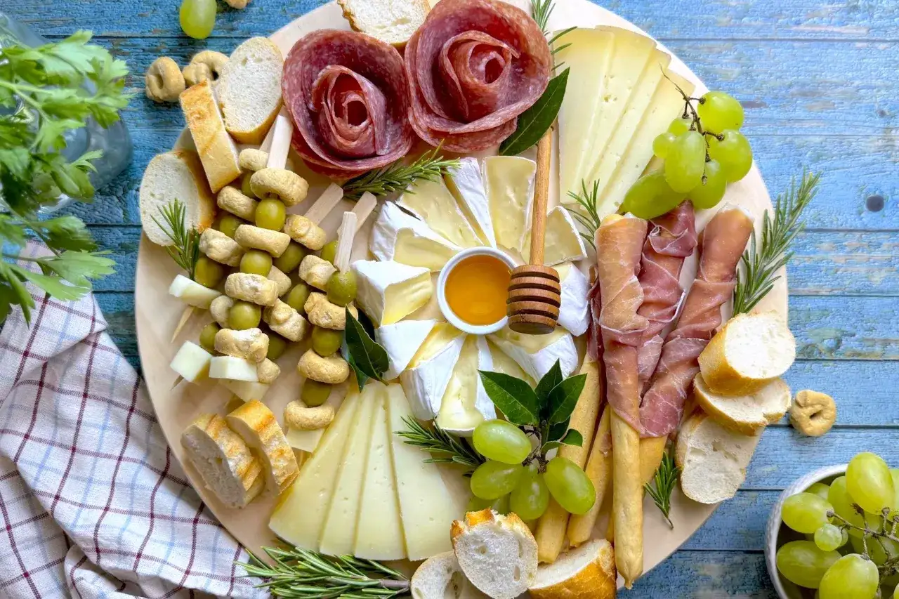 Un invitante tagliere di salumi per aperitivo con formaggi, olive, uva, pane e miele, perfetto per un momento di convivialità.