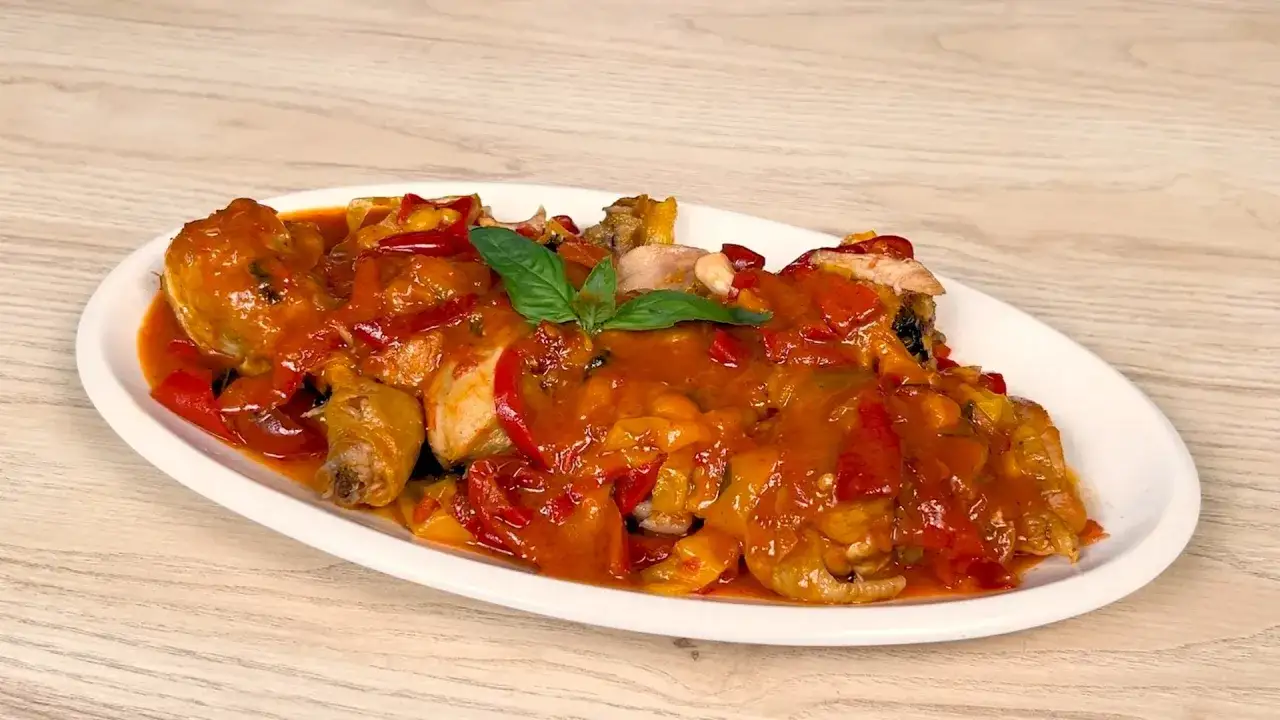 Pollo alla romana succulento con peperoni rossi e gialli, guarnito con basilico fresco.