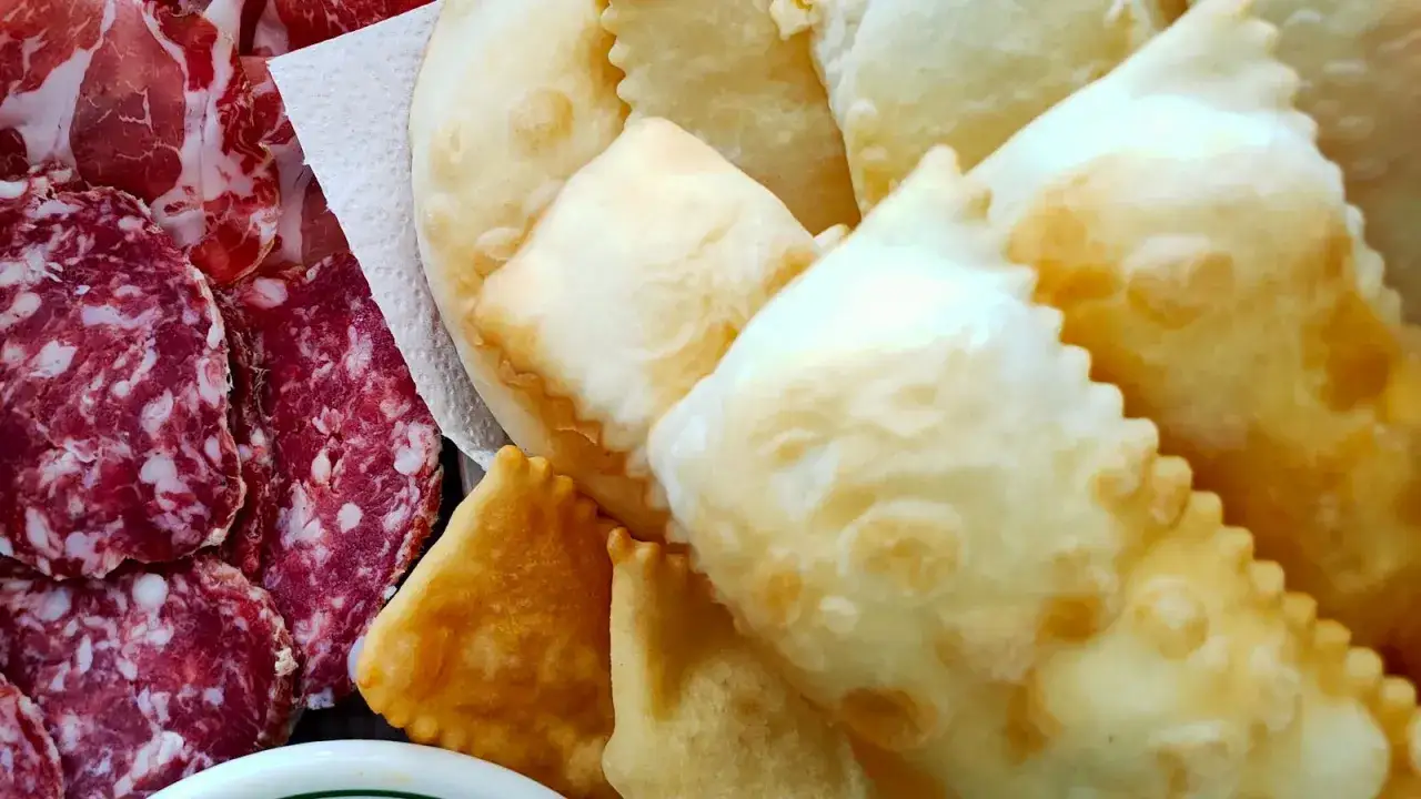 Piatto di salumi misti e gnocco fritto dorato e fragrante, pronto per essere gustato.