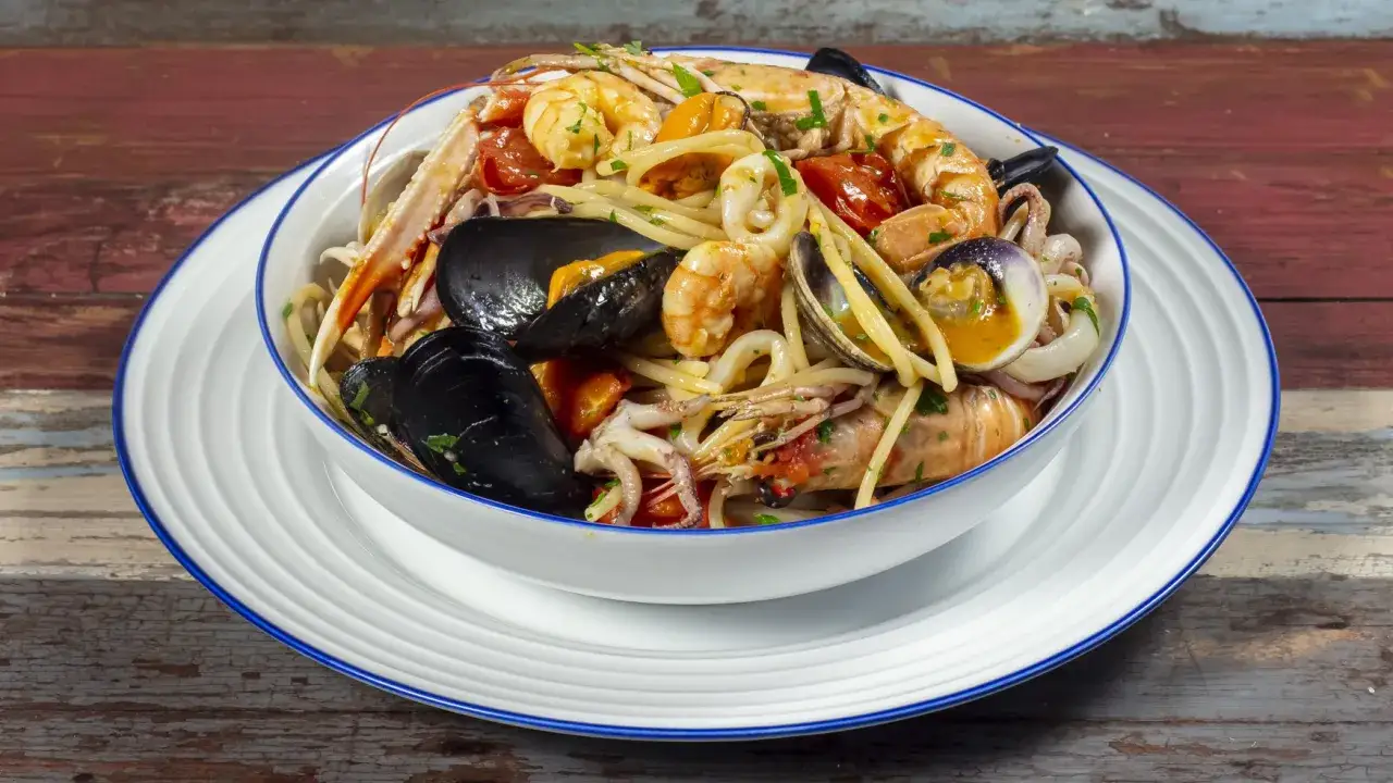 Un invitante piatto di spaghetti allo scoglio, ricco di gamberi, cozze, vongole e calamari, pronto per essere gustato.
