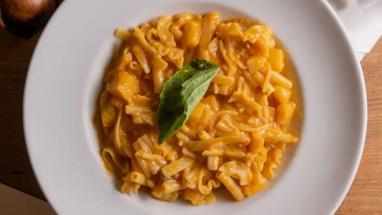 Piatto di pasta patate e provola, con un rametto di basilico fresco. Cremoso e invitante, un classico comfort food.