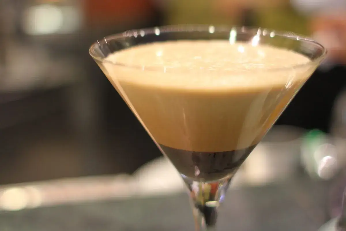Un bicchiere di caff&egrave; shakerato con strati di crema e caff&egrave; scuro.