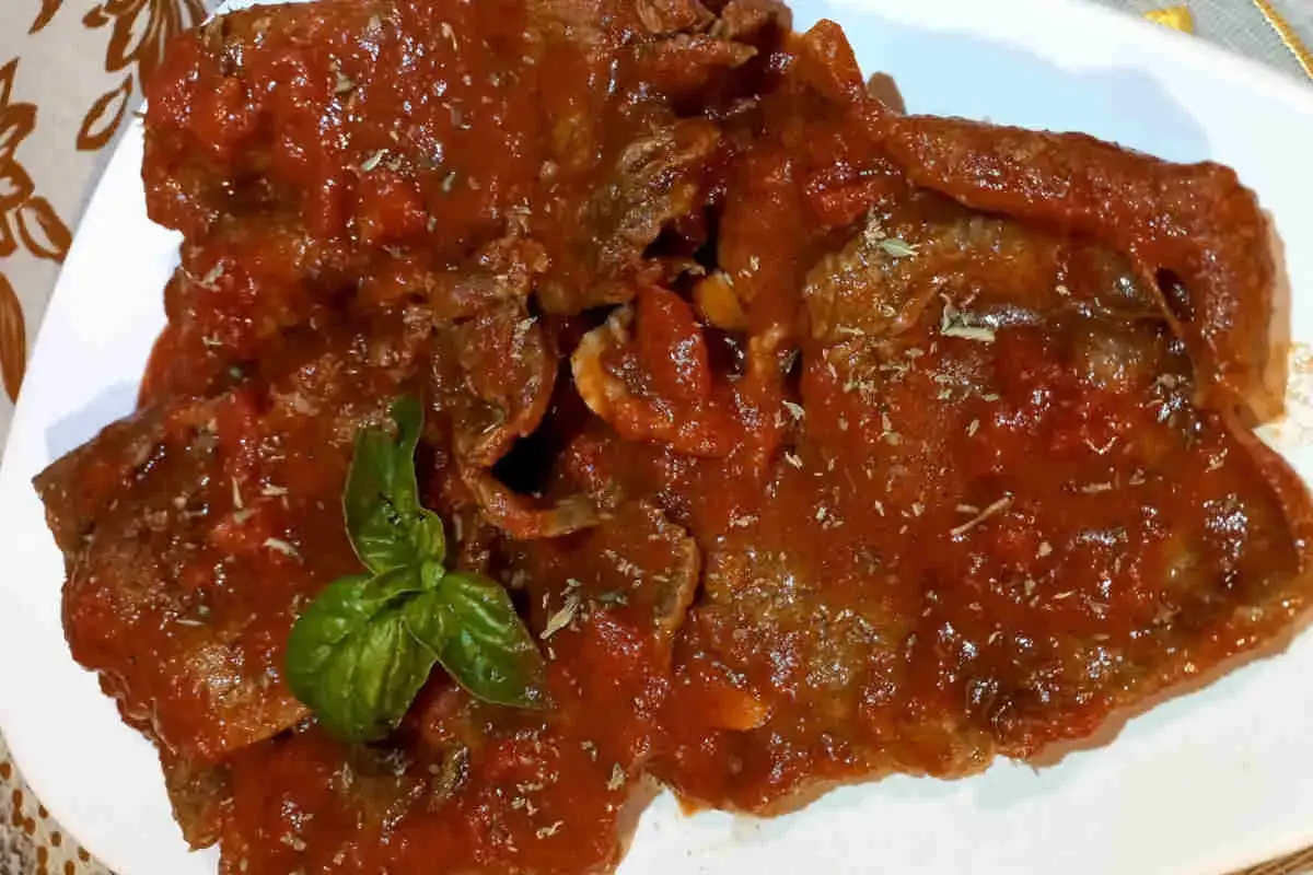 Fette di carne alla pizzaiola, succulente e profumate, condite con salsa di pomodoro e basilico fresco.